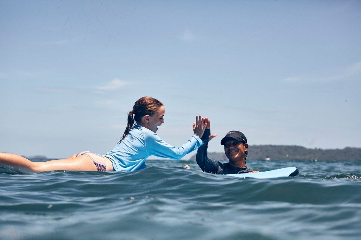 family surf trip child high fiving instructor