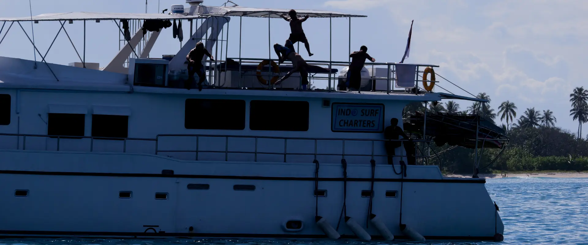 People diving off a large charter boat into ocean