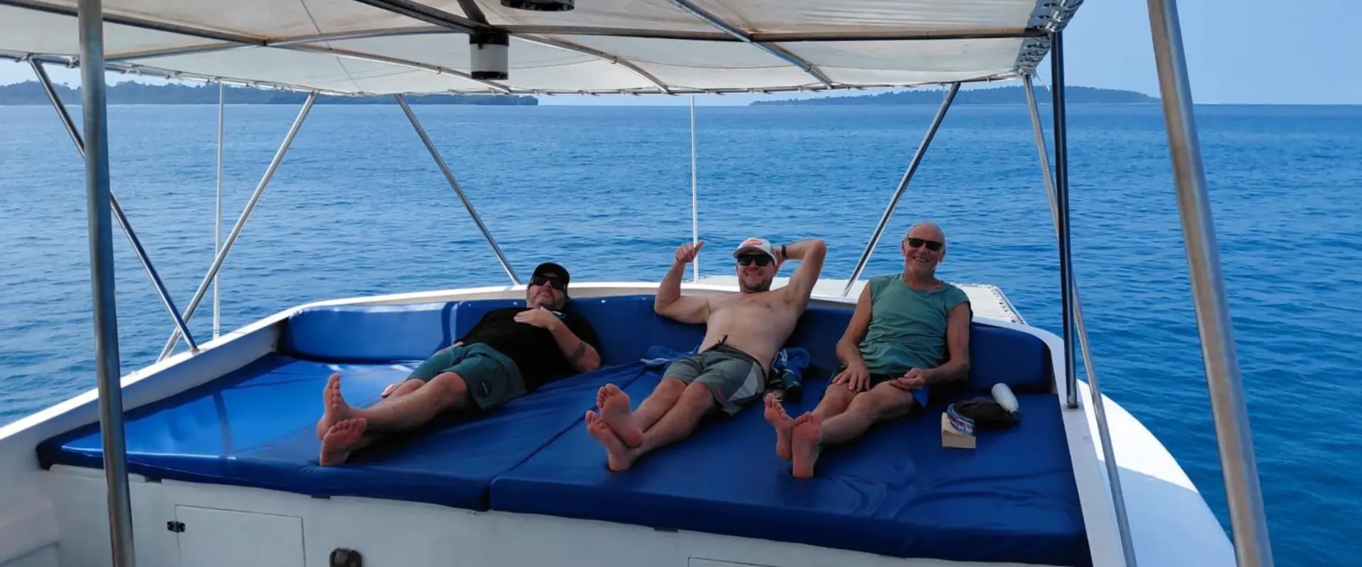 Three men relaxing on blue boat cushions at sea