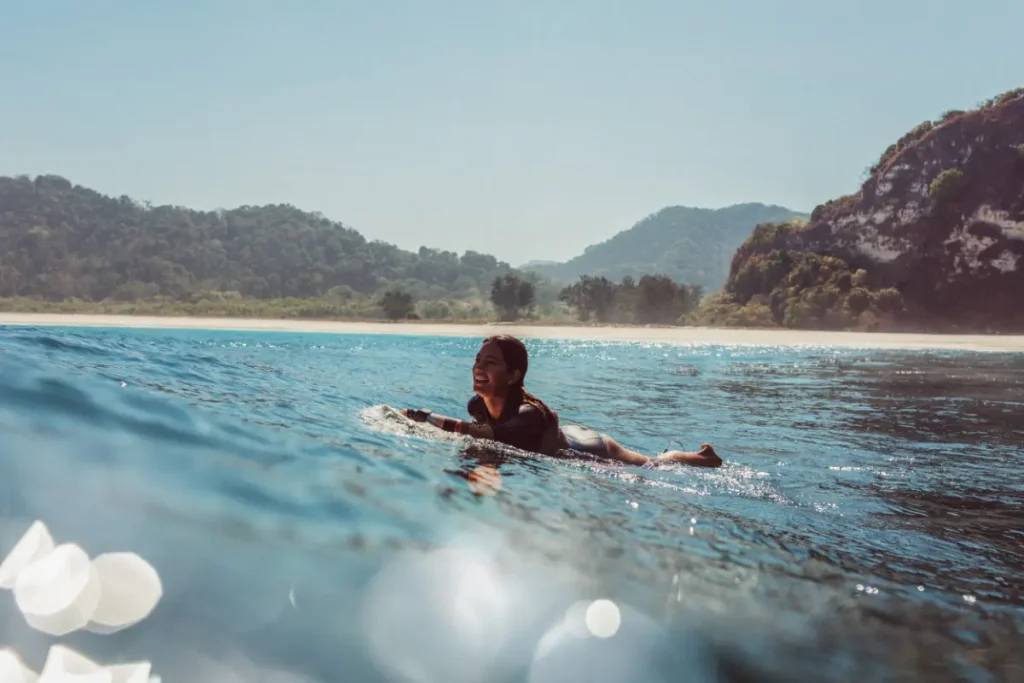 girl surfer prone on surfboard enjoying sea waves