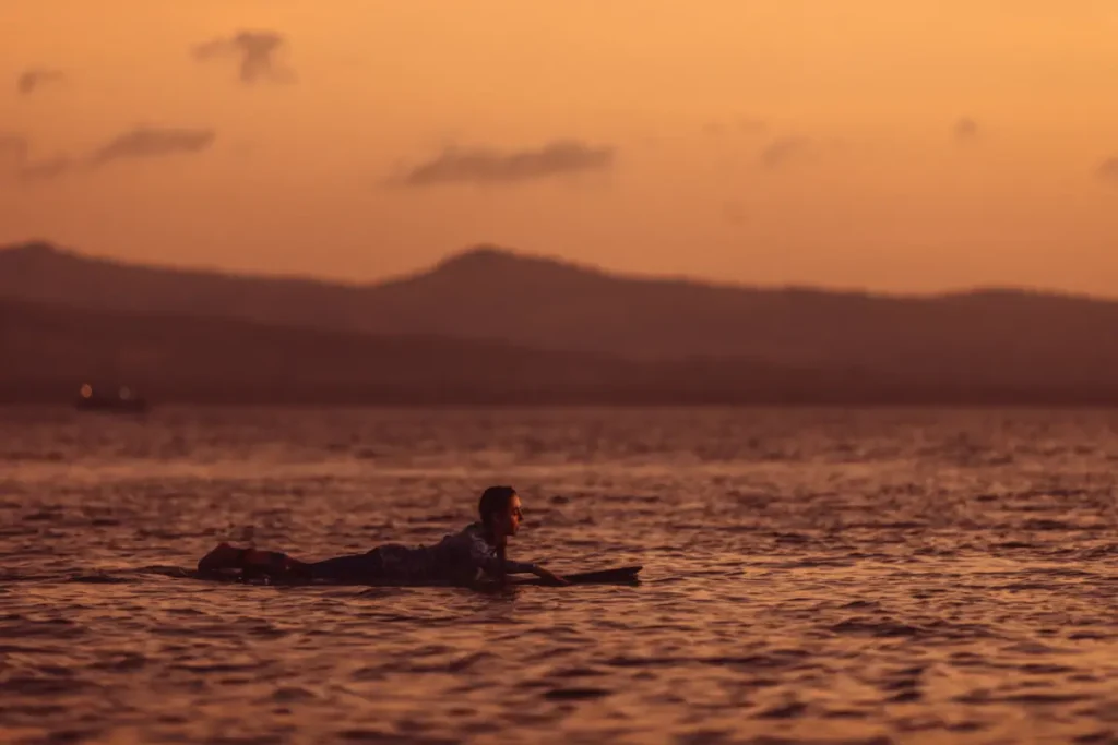 surfer lies prone on a surfboard