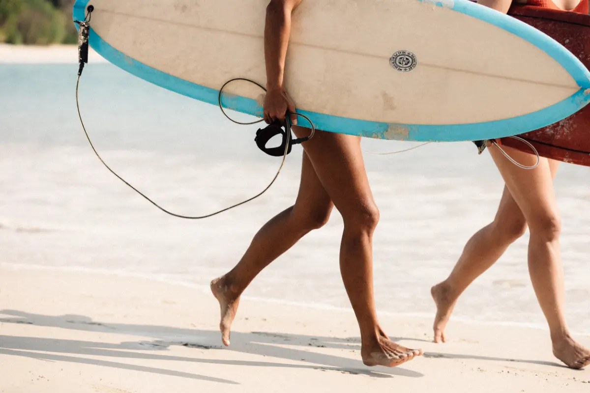 two peoples holding surf board