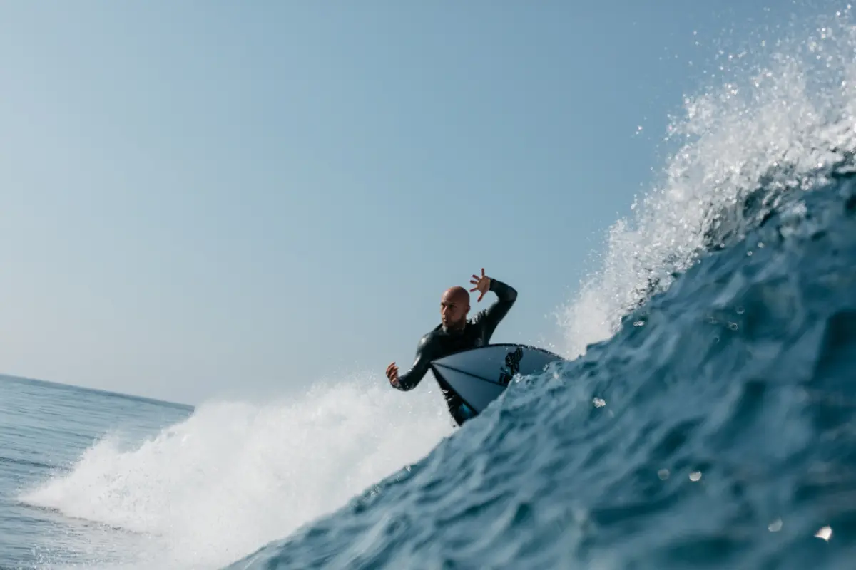 black wetsuit rides a breaking blue wave